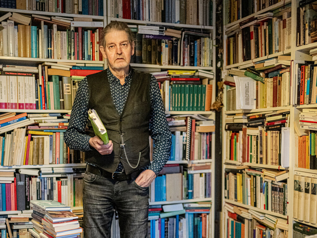 Josef Oberhollenzer, inmitten der Bücher, die sein Schreiben stützen: „Läuft die Literatur der Wirklichkeit hinterher oder die Wirklichkeit der Literatur?“ Foto: Harald Wisthaler