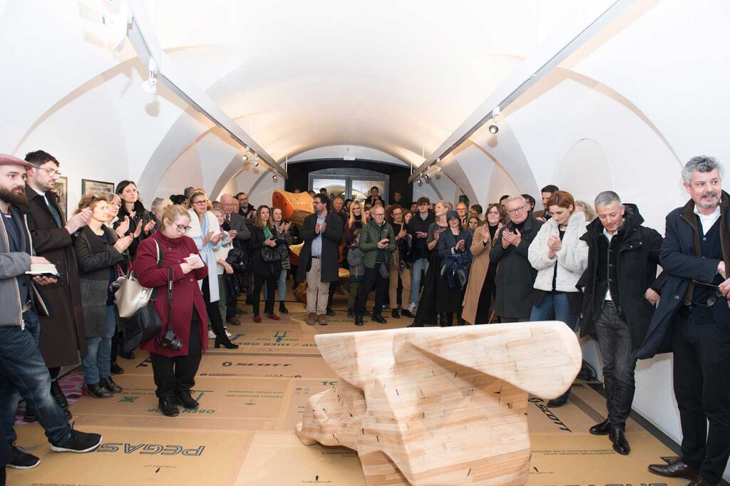 Überraschend großer Andrang bei der Eröffnung von „Zwischenraum“ in der Stadtgalerie Brixen. Auf dem mit Fahrradkartons ausgelegten Boden sind Holzskulpturen des Künstlers Peter Sandbichler zu sehen. Foto: Leonhard Angerer