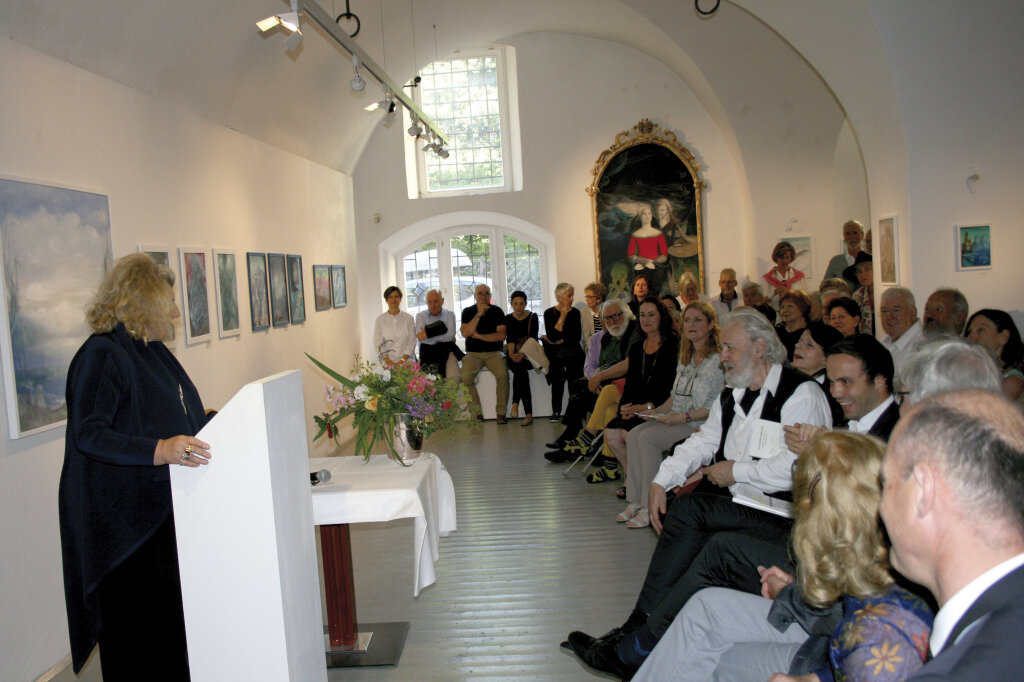 Geburtstagsgrüße: Helga von Aufschnaiter am Podium, Luis Stefan Stecher (der Herr mit Bart in der ersten Reihe). Foto: Südtiroler Künstlerbund