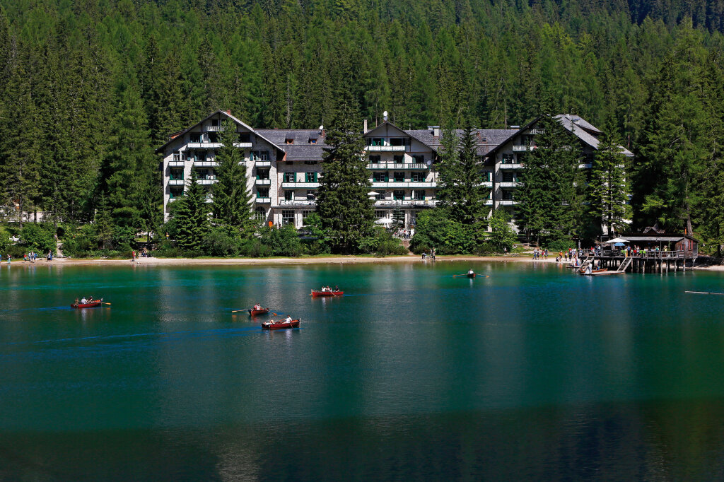 Der Pragser Wildsee und das Grandhotel der Familie Heiss: Ruderboote treiben wie Nussschalen auf dem Wasser, weiter oben sieht man noch kleine Schneefelder zwischen massiven Bergflanken – doch die Idylle trügt. Foto: Alexander Alber