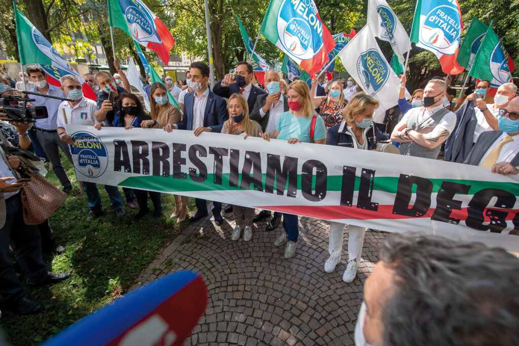 Wahlkampf als Protestzug im Bozner Bahnhofpark: FdI-Chefin Giorgia Meloni (Mitte), begleitet von den hinter ihr stehenden lokalen Parteigrößen Marco Galateo (dunkelblaue Maske) und Alessandro Urzì (hellblaue Maske). Foto: Othmar Seehause